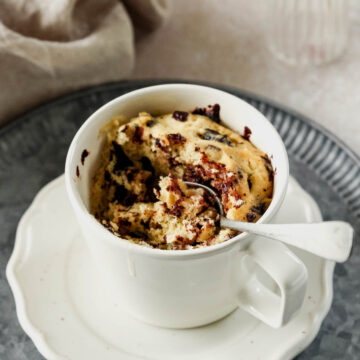 chocolate chip mug cake in off-white mug with vintage spoon in cake.