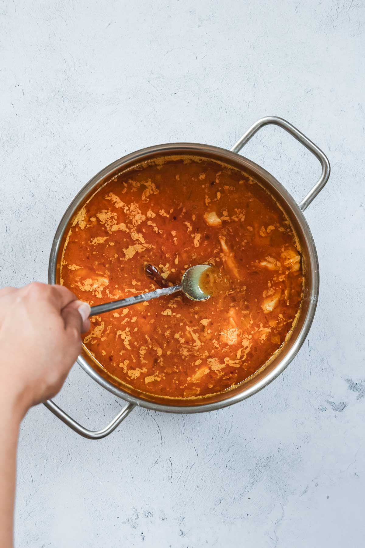 bringing curry ingredients in pot to a poil while stirring with spoon.