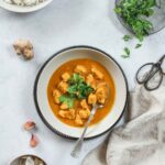 chicken curry with parsley garnish in grey bowl with vintage spoon.