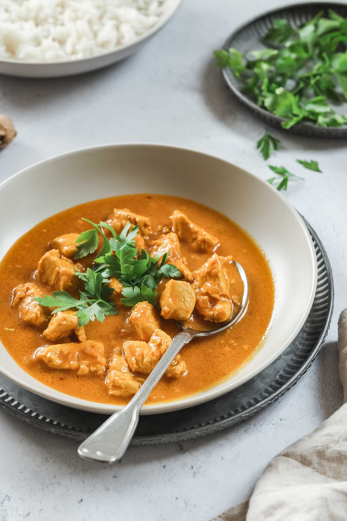 closeup of chicken curry in grey bowl with vintage spoon.