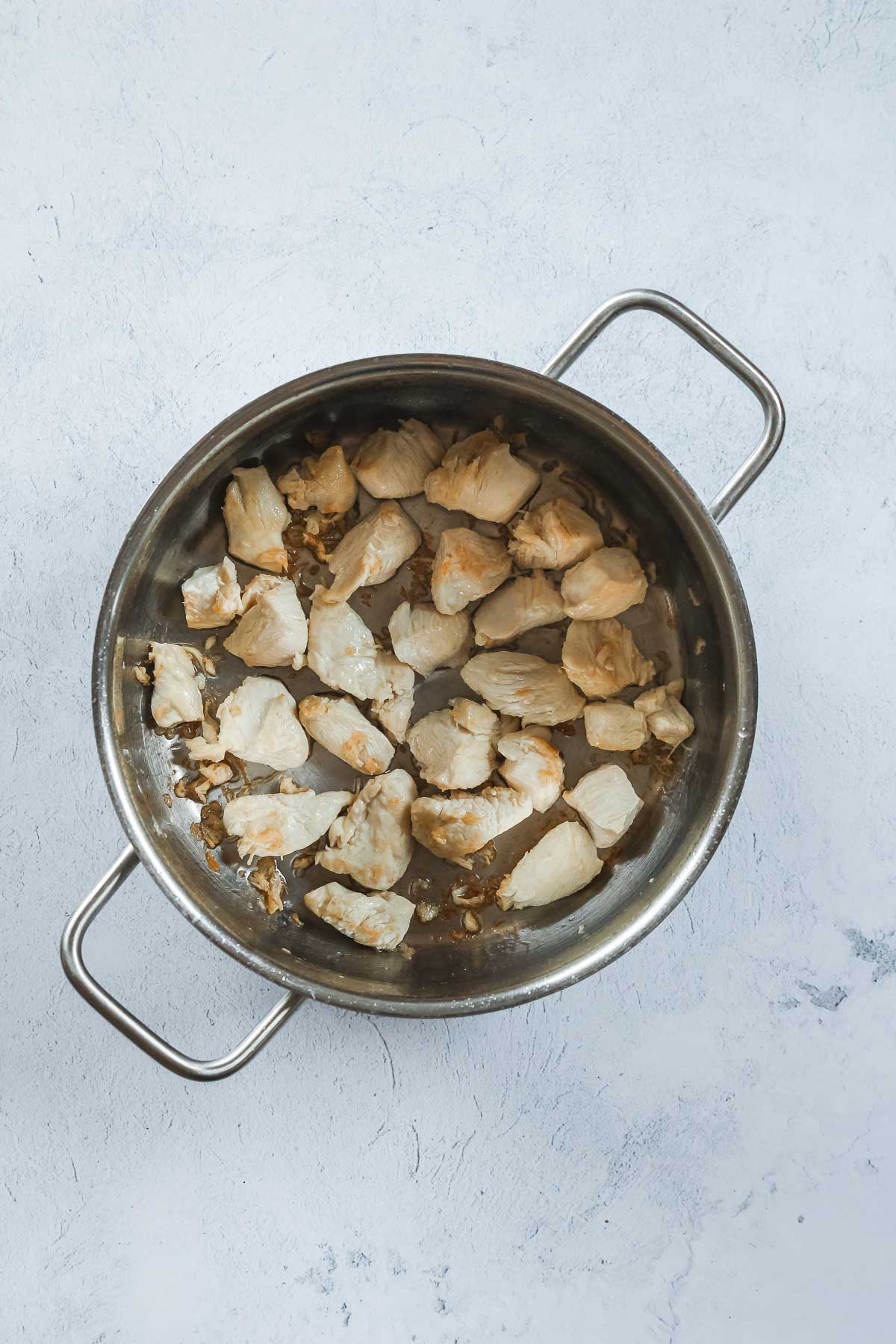 cut chicken breast roasting in pot with oil.