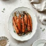 air fryer roasted carrots on a serving platter topped with herbs and spices.