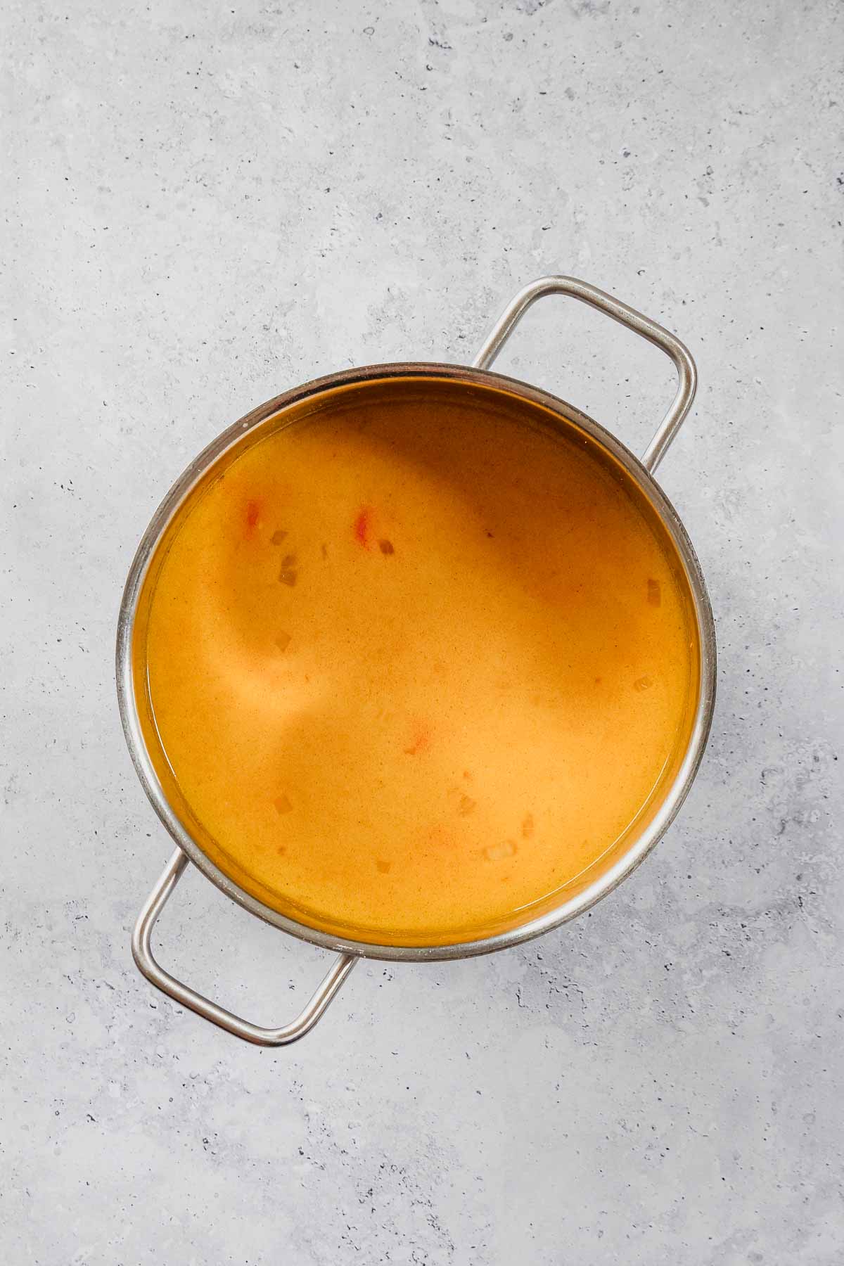 ingredients for carrot ginger soup cooking in pot.