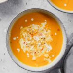 carrot soup with curry and coconut milk in blue bowls with props.