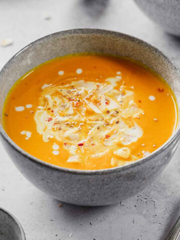 carrot soup with curry and coconut milk in blue bowls with props.