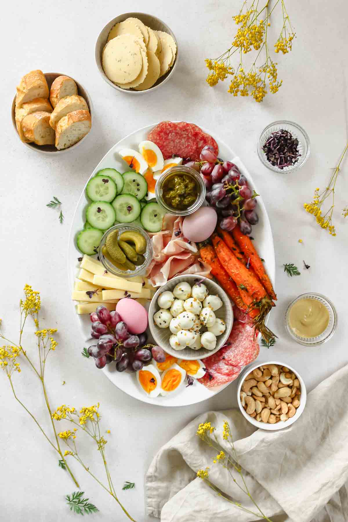 easy easter charcuterie board placed on grey background with props and spring flowers.