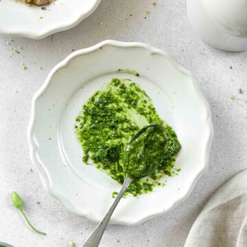 easy easy wild garlic pesto on a vintage spoon laying on a plate with props in the background.