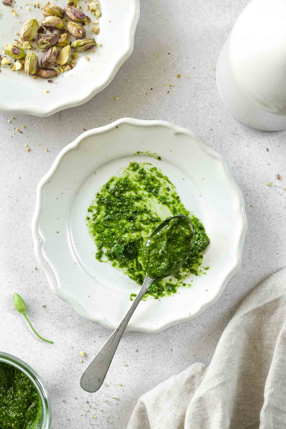 easy easy wild garlic pesto on a vintage spoon laying on a plate with props in the background.