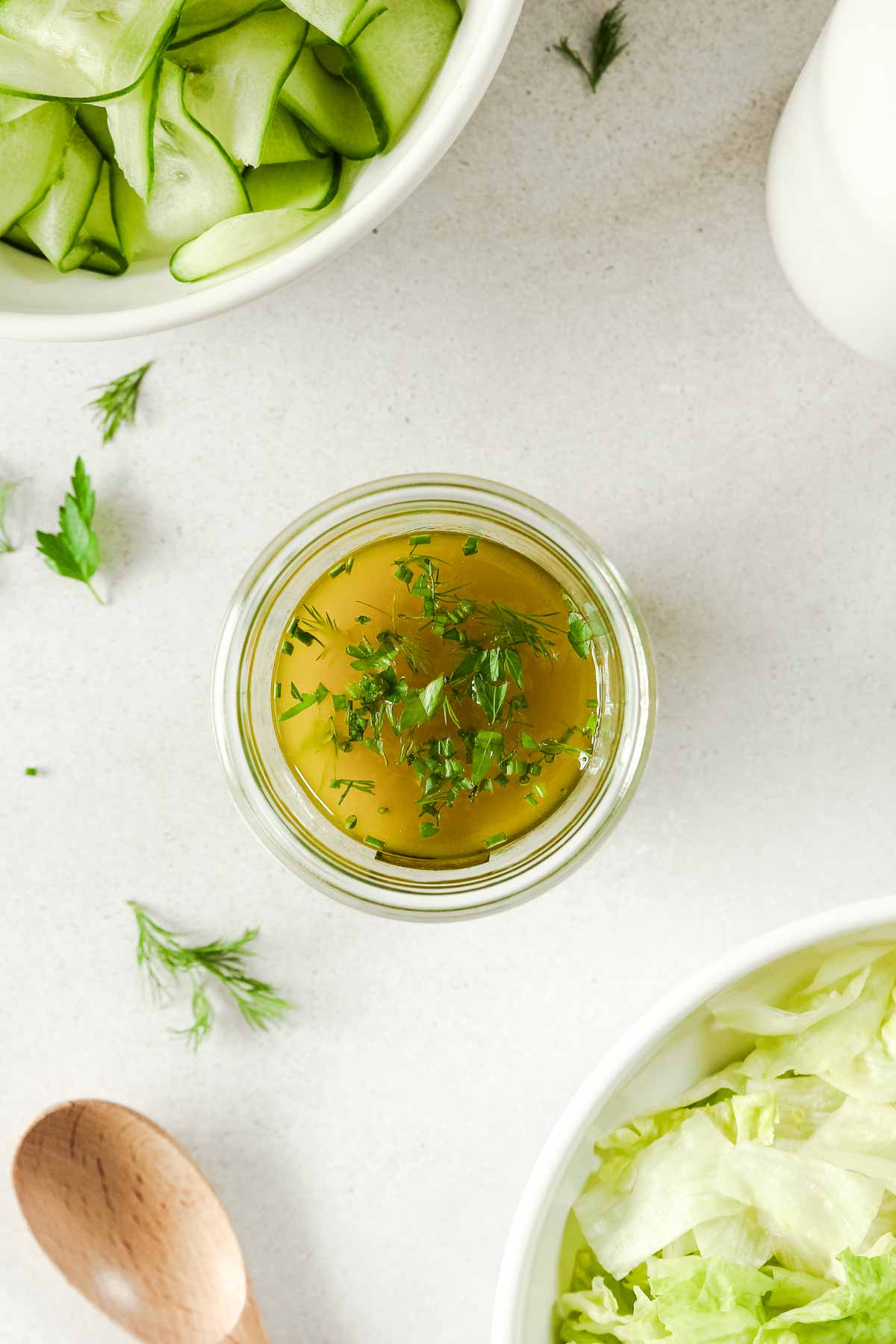 lemon herb vinaigrette in clear jar with salads in background.