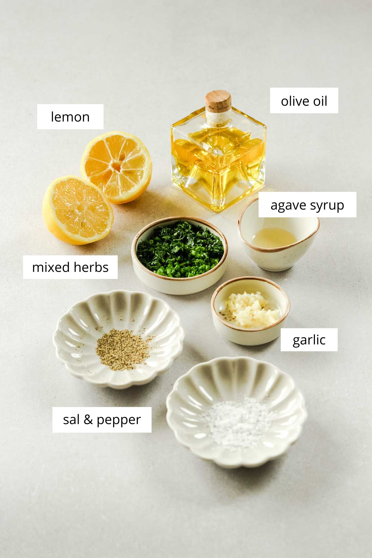 ingredients for simple lemon herb vinaigrette dressing on beige background.