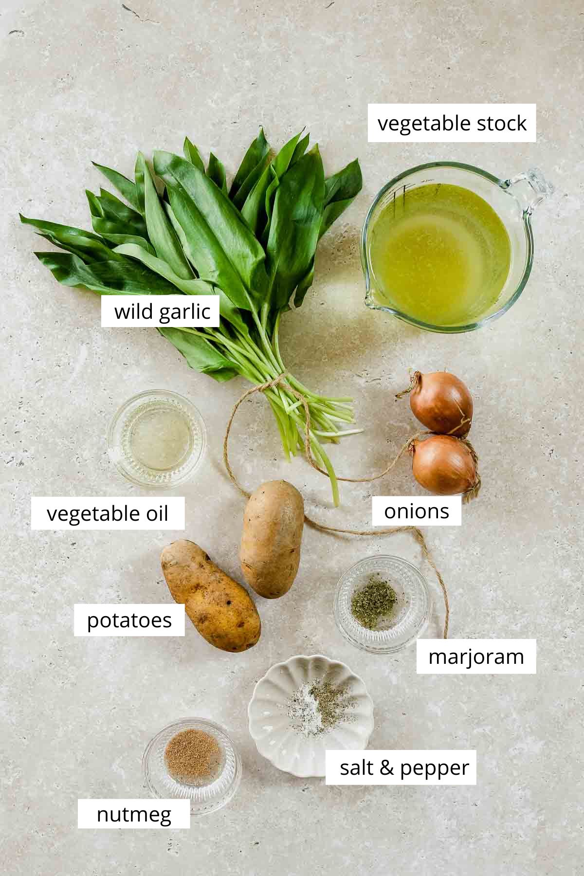 ingredients for vegan wild garlic and potato soup on a beige background with labels.