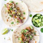 healthy chicken tortilla wraps with red onions, cucumber and tahini on white background.