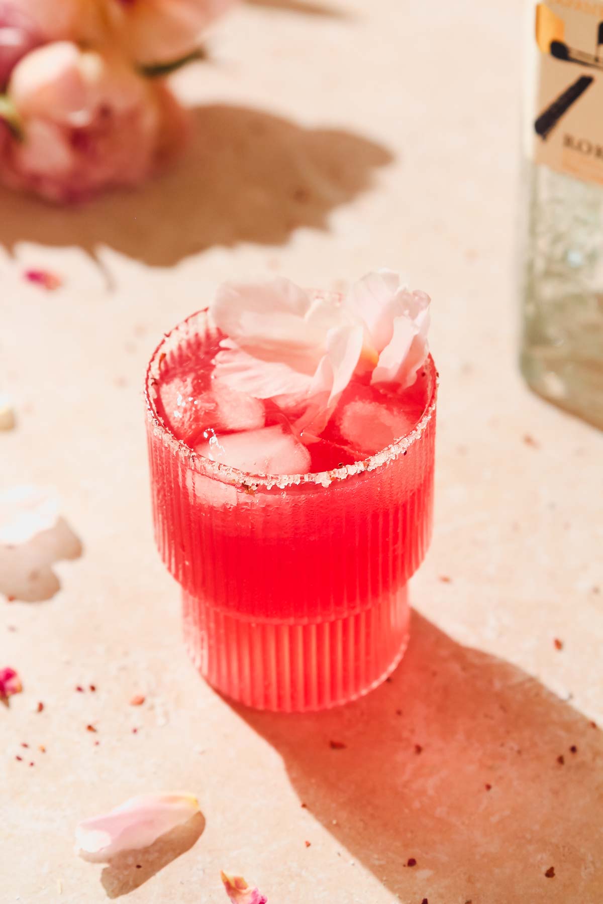 floradora gin cocktail with peony decoration on beige background.