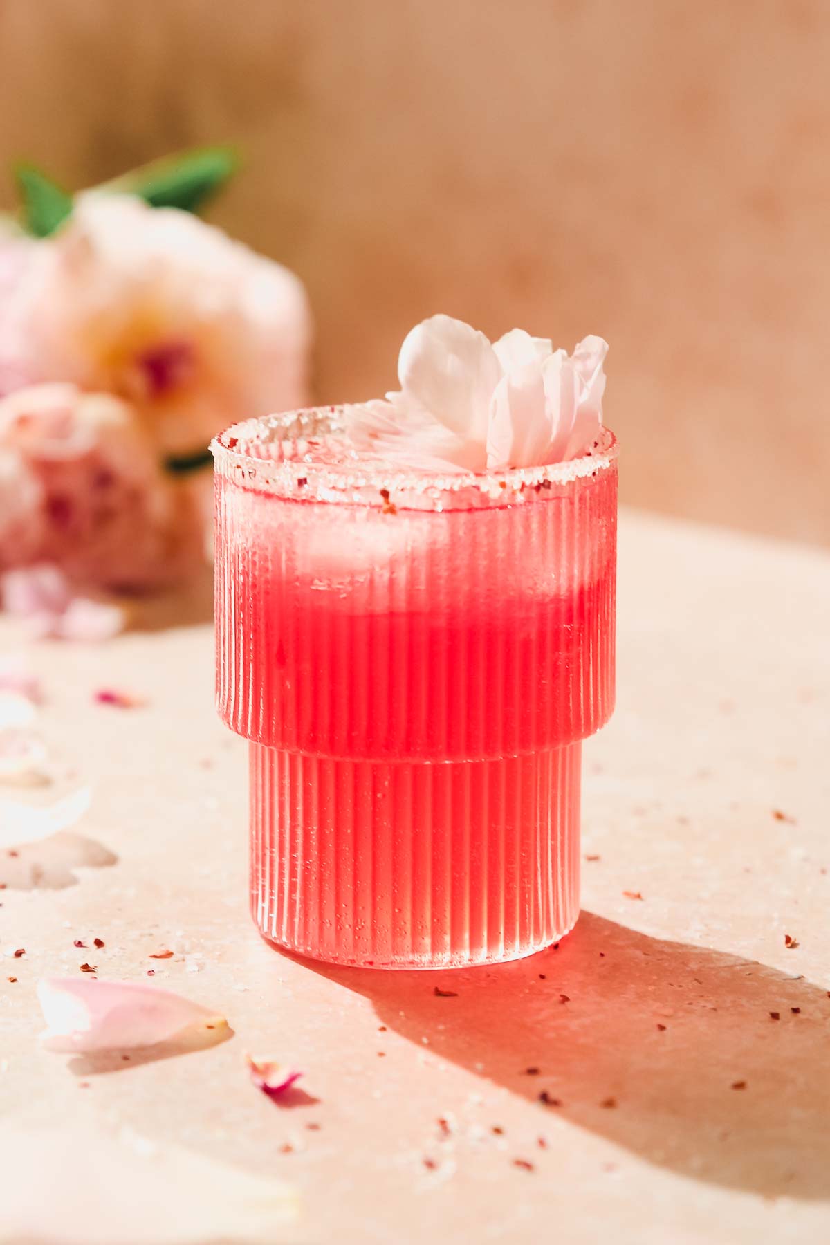 floradora gin cocktail with peony decoration on beige background.