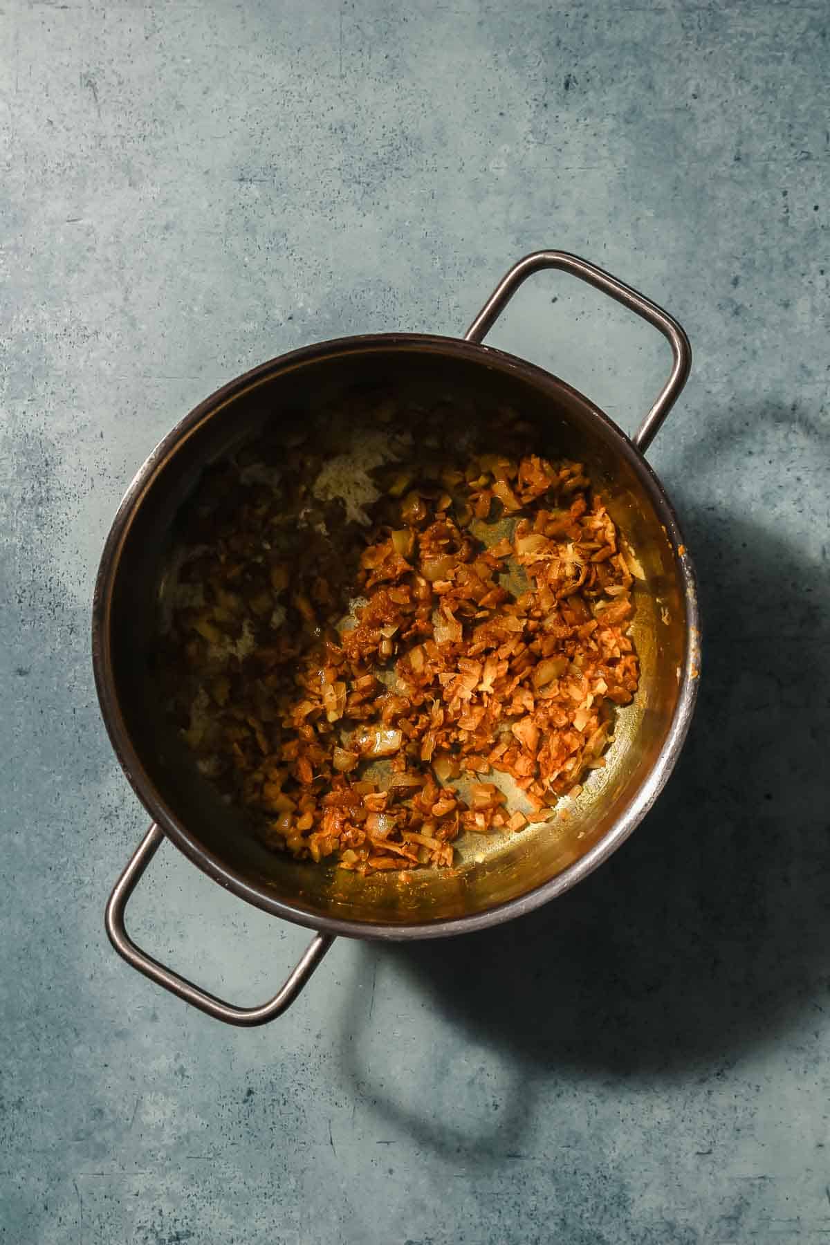 roasting onion, garlic and spices for yellow curry paste in pot.