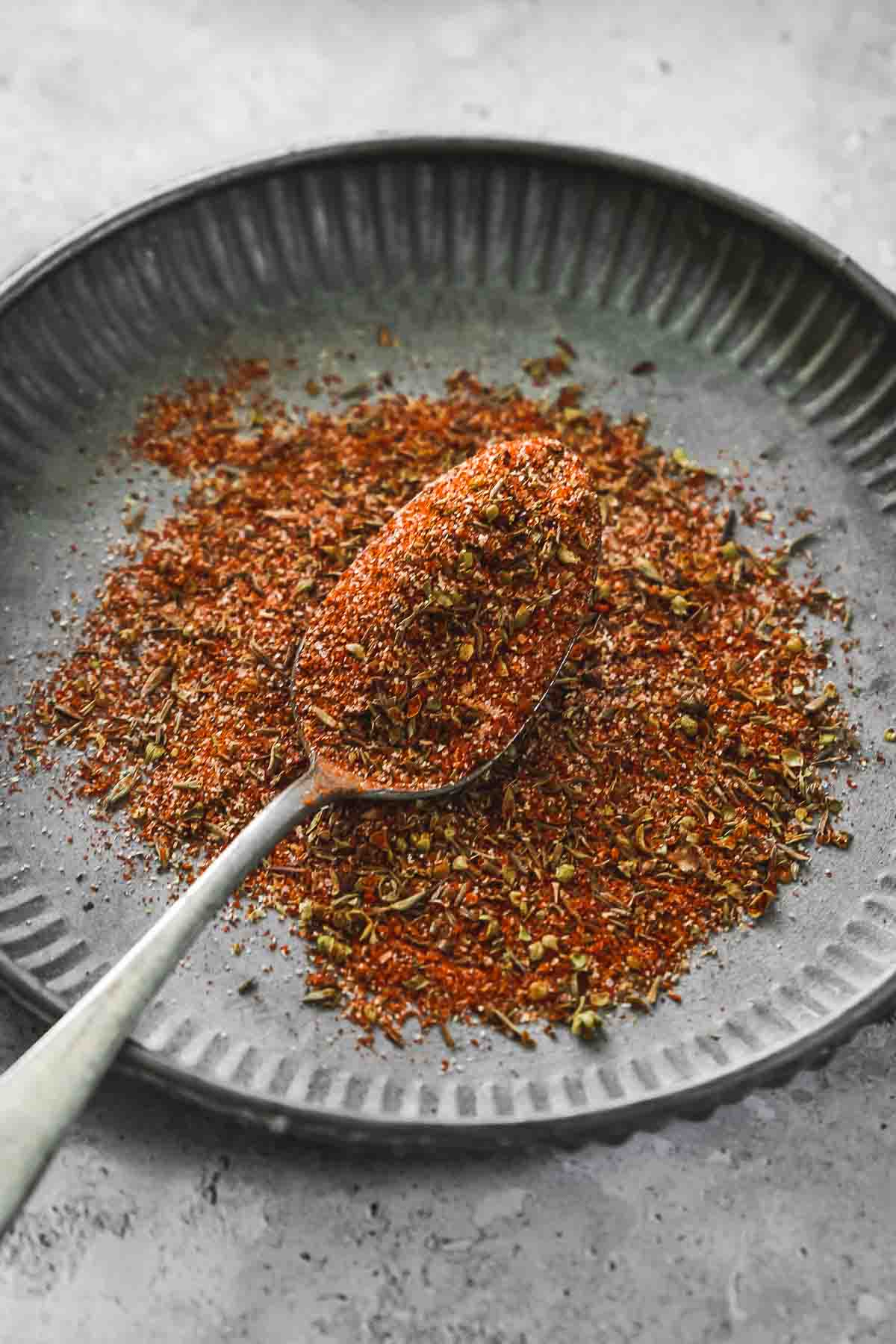 mixed DIY cajun seasoning on vintage plate with spoon.