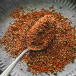 mixed homemade cajun seasoning on vintage plate with spoon.