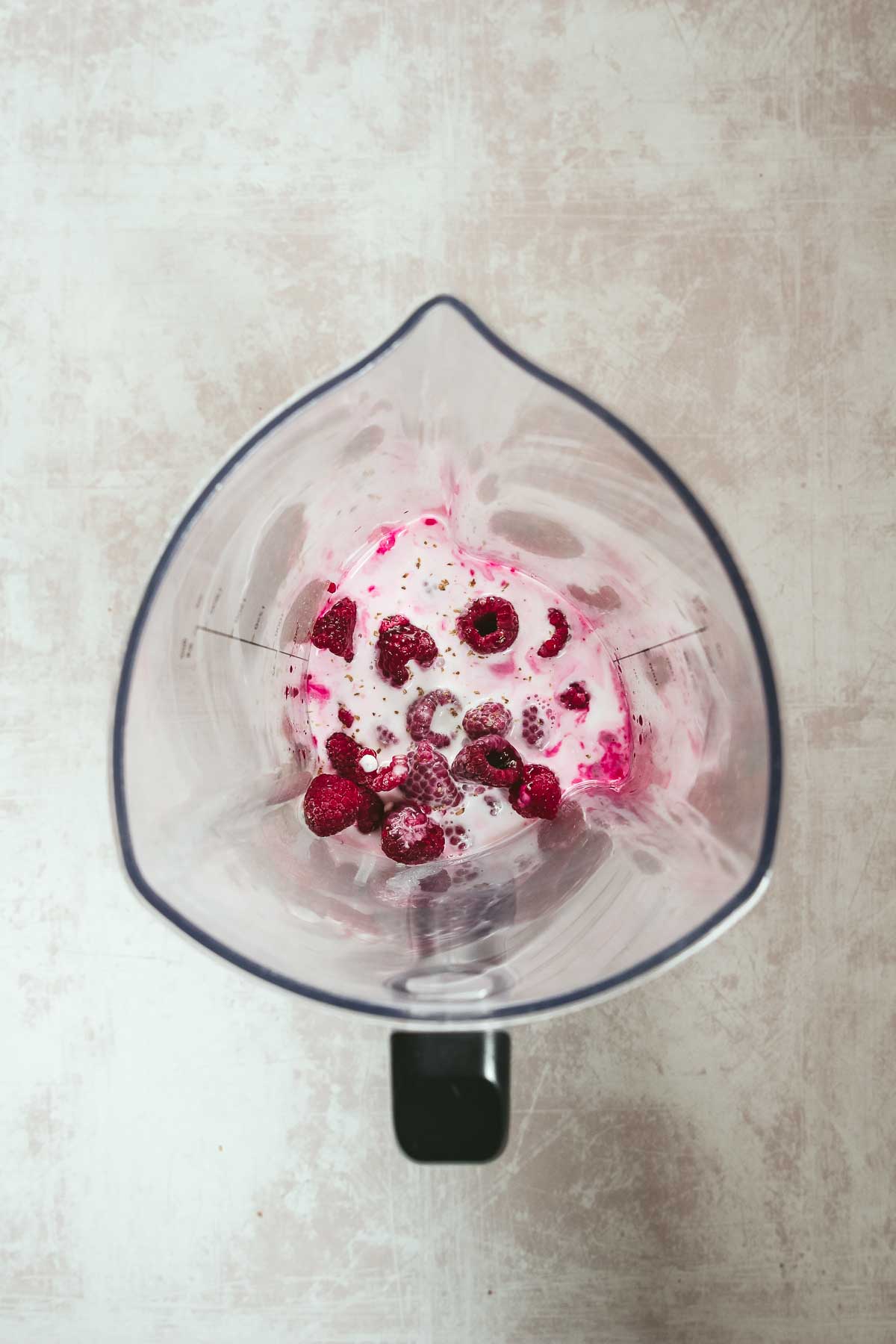 ingredients for hot pink breakfast smoothie in blender on rosy background.