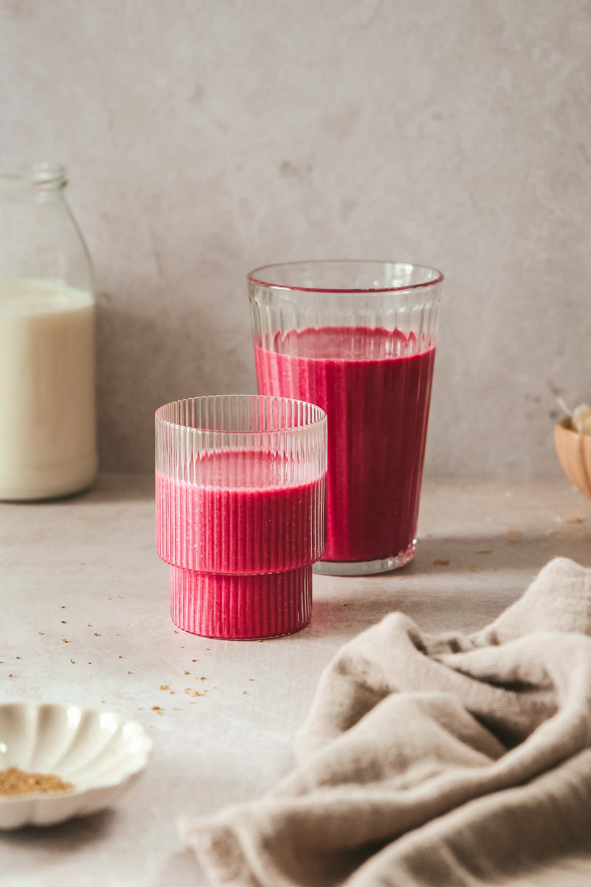 pink smoothie in different glasses on beige background.