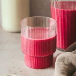 pink smoothie in different glasses on beige background.