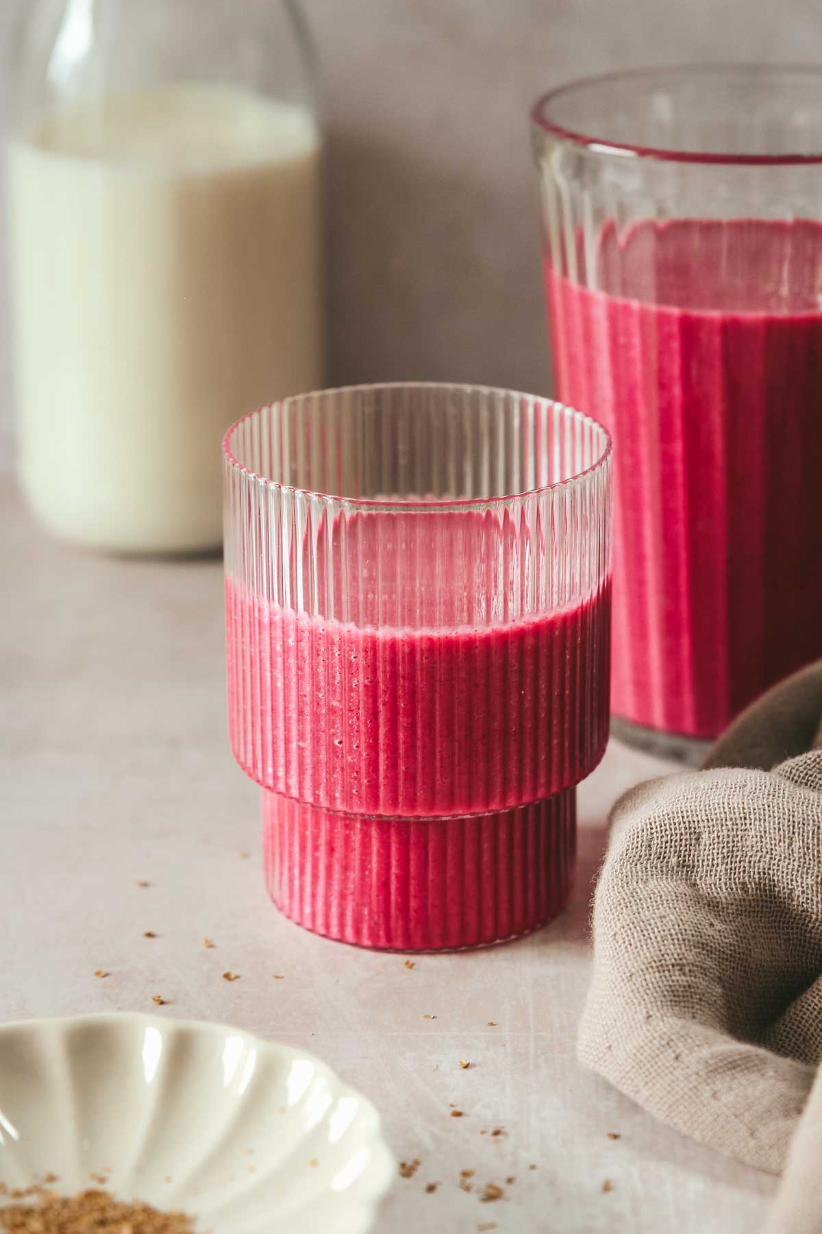 pink smoothie in different glasses on beige background.