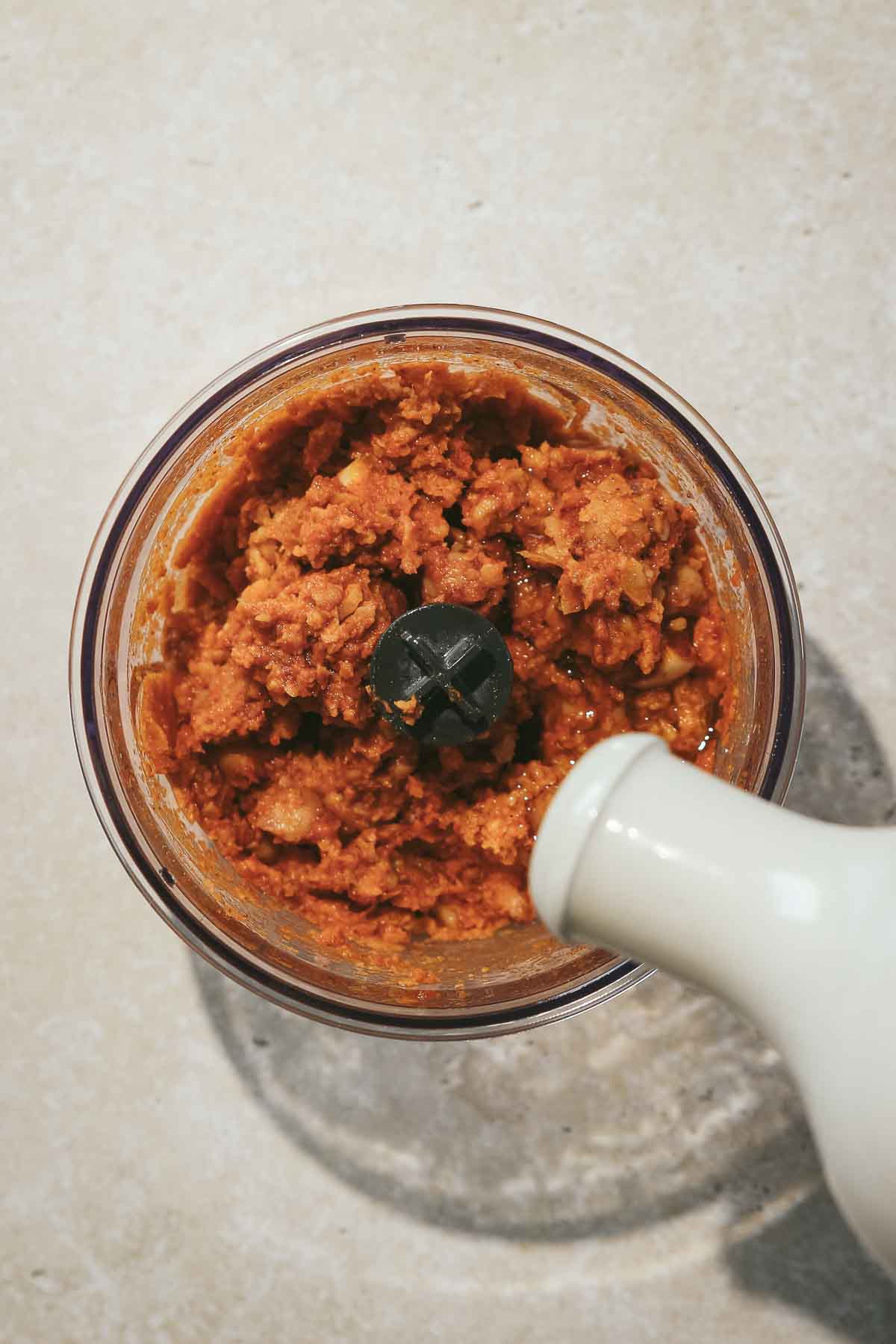 adding olive oil to spiced hummus.