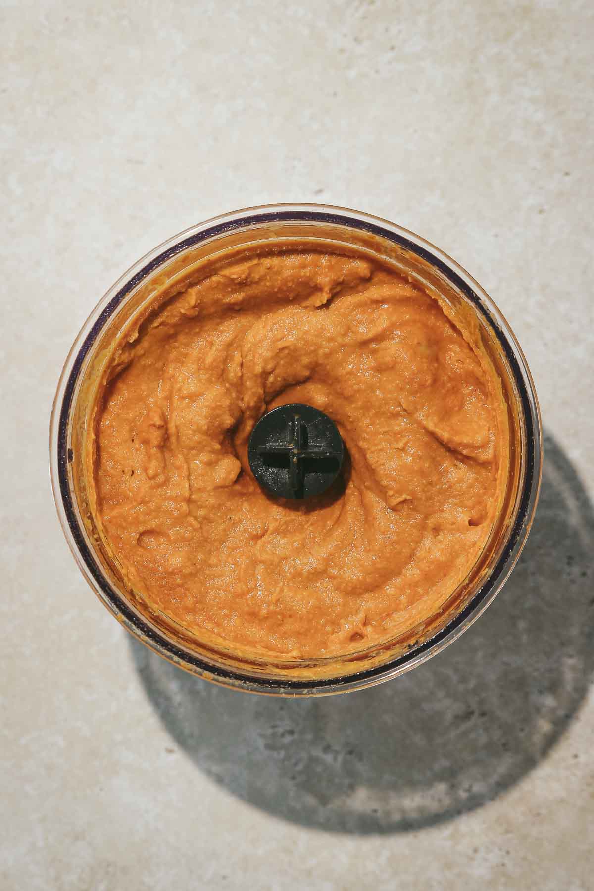 mixing spicy hummus in food processor.