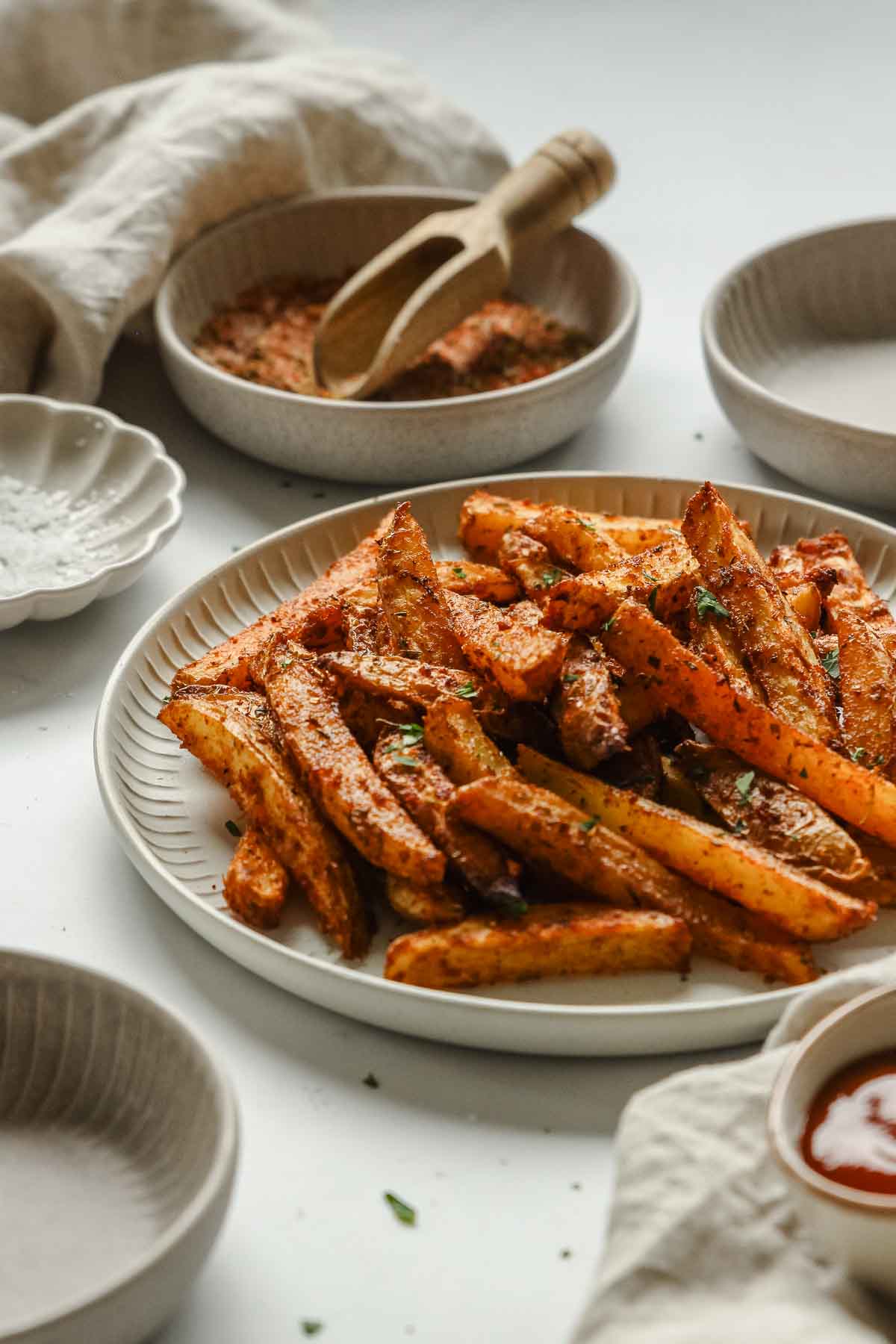 closeup of oven baked cajun fries on white plate.