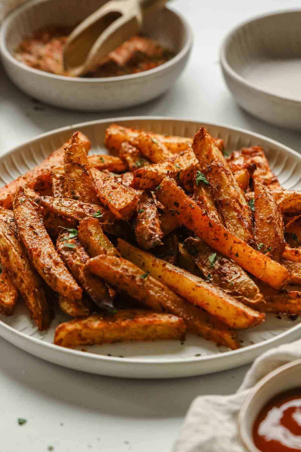 closeup of oven baked cajun fries on white plate.