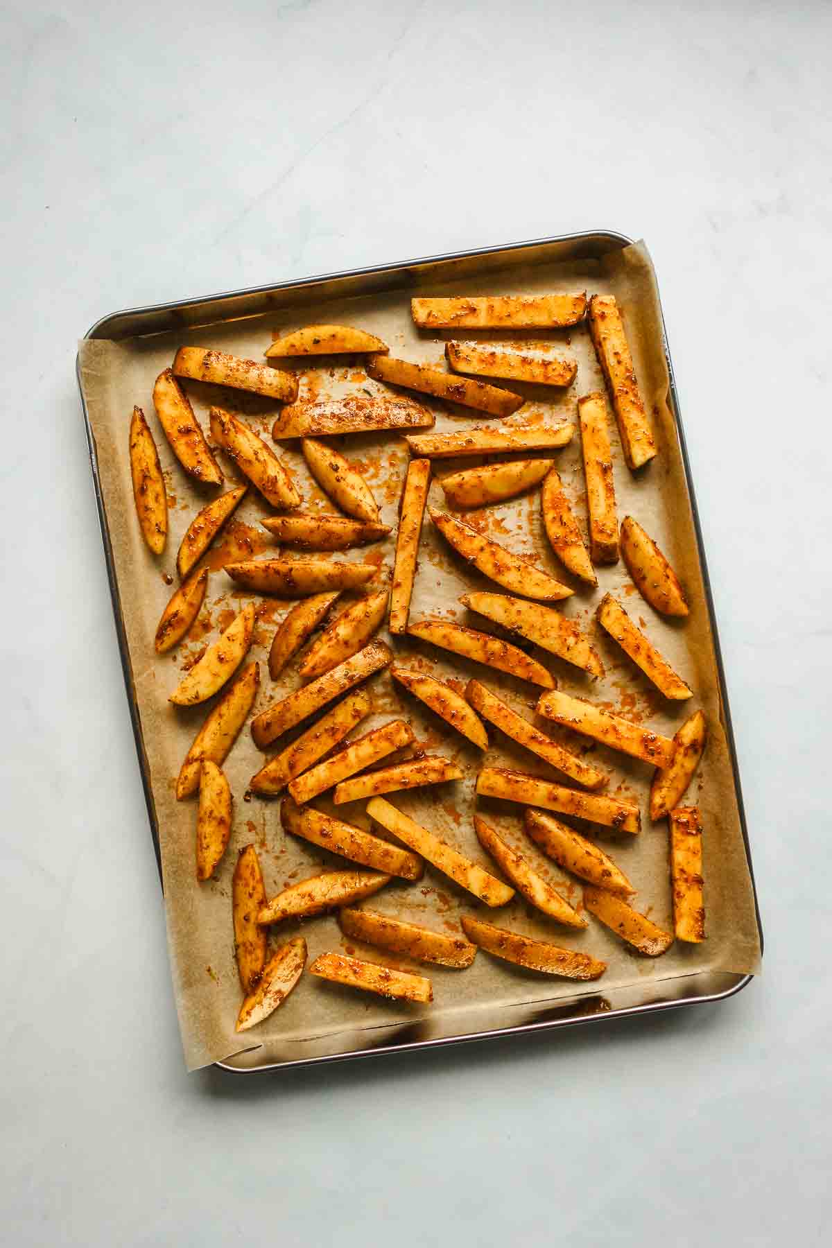 cajun seasoned fries on baking sheet with parchment paper.