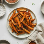 cajun style fries on white plate with parsley sprinkled on.