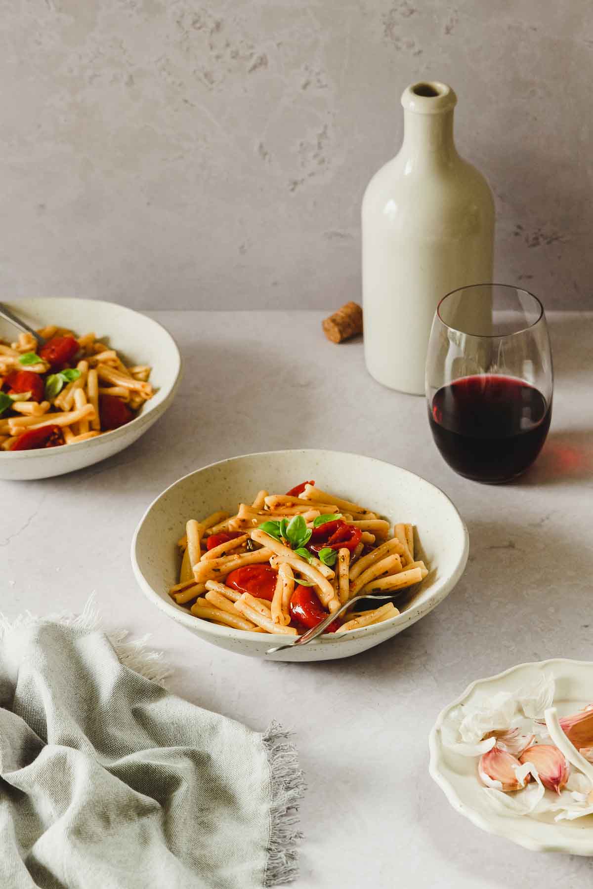 roasted cherry tomato pasta in beige bowl with vintage fork an props.