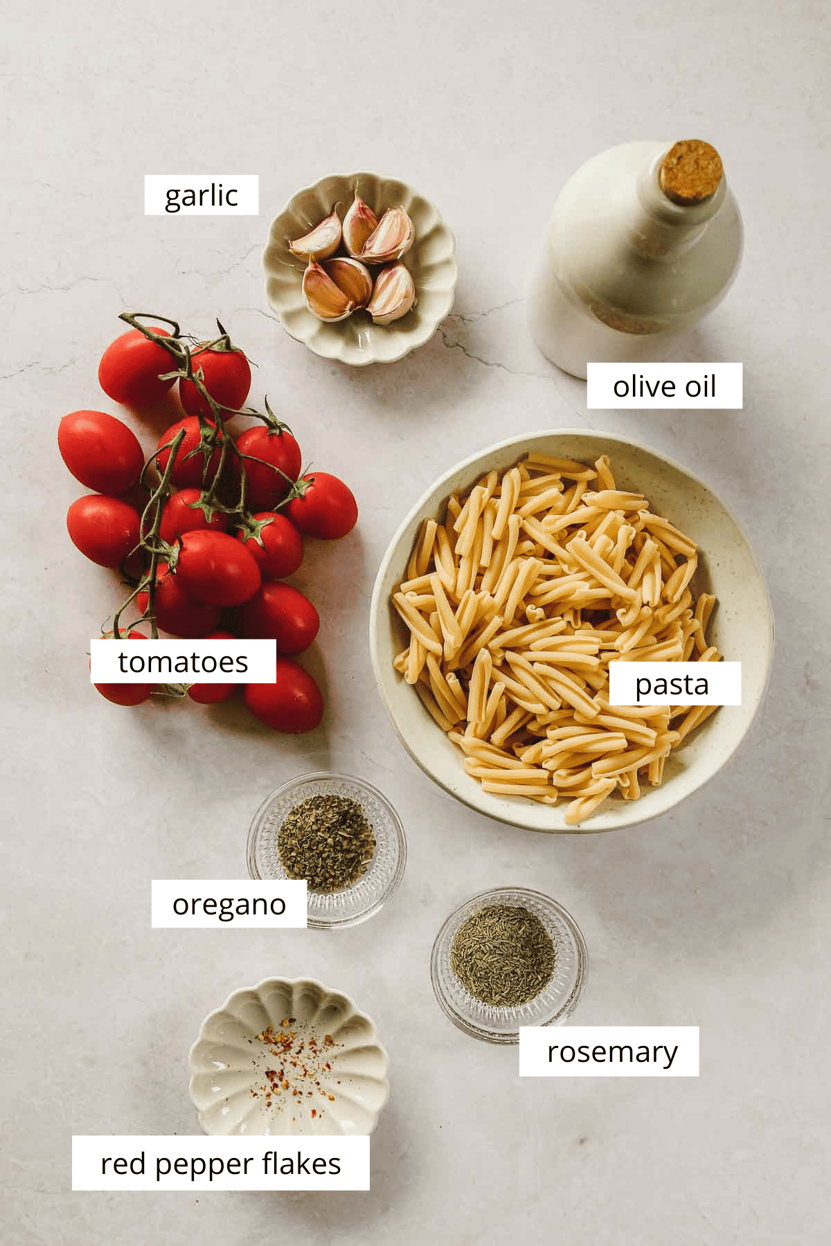 ingredients for oven roasted tomato pasta on beige marble background.