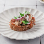 closeup of sardine bruschetta on scalloped plate.