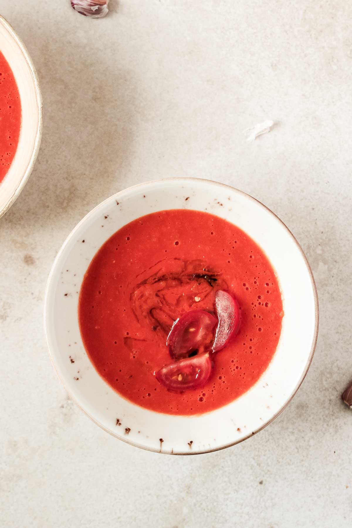 homemade roasted tomato soup in beige speckled bowl on beige background.