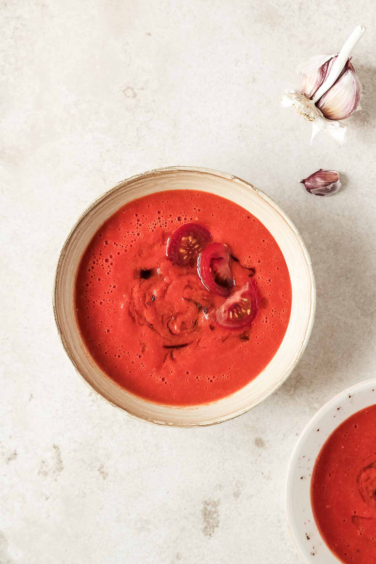 easy oven roasted tomato soup in beige bowls on beige background.