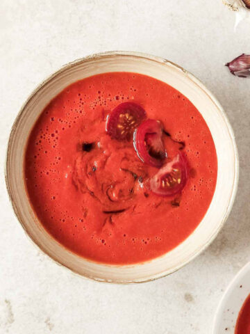 homemade roasted tomato soup in beige speckled bowl on beige background.