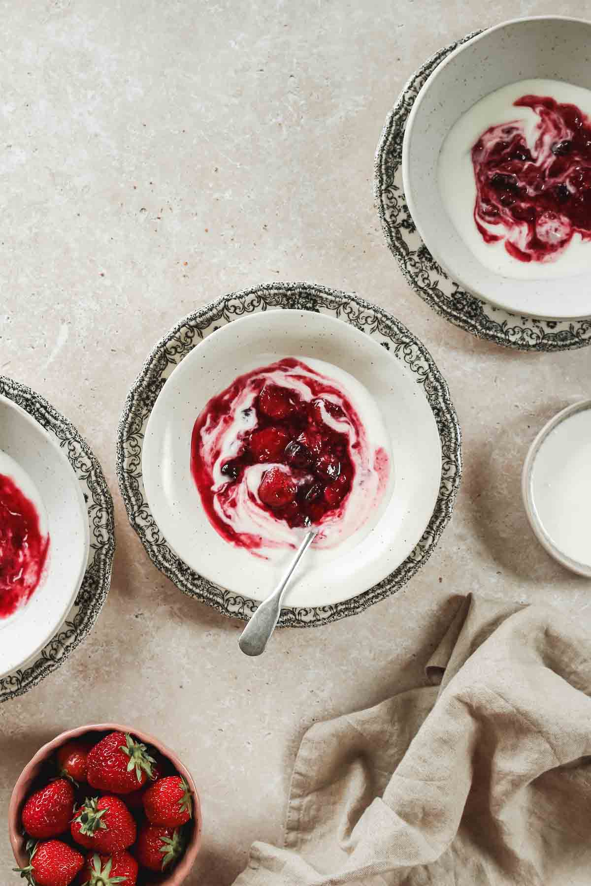 easy mixed berry compote on beige bowls on flower plates with vintage spoon.