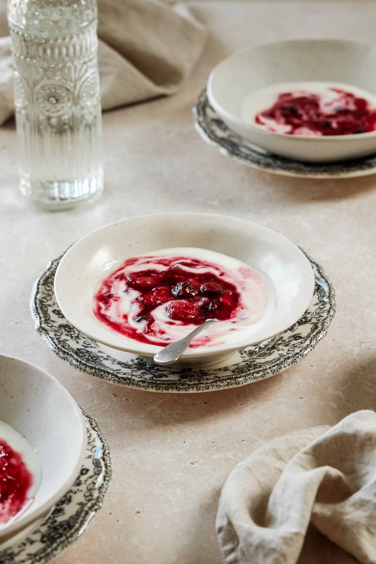 quick mixed berry compote in beige bowls on plates with flowers and vintage spoon.