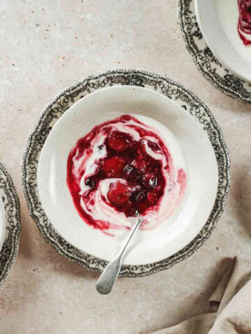 easy mixed berry compote on beige bowls on flower plates with vintage spoon.