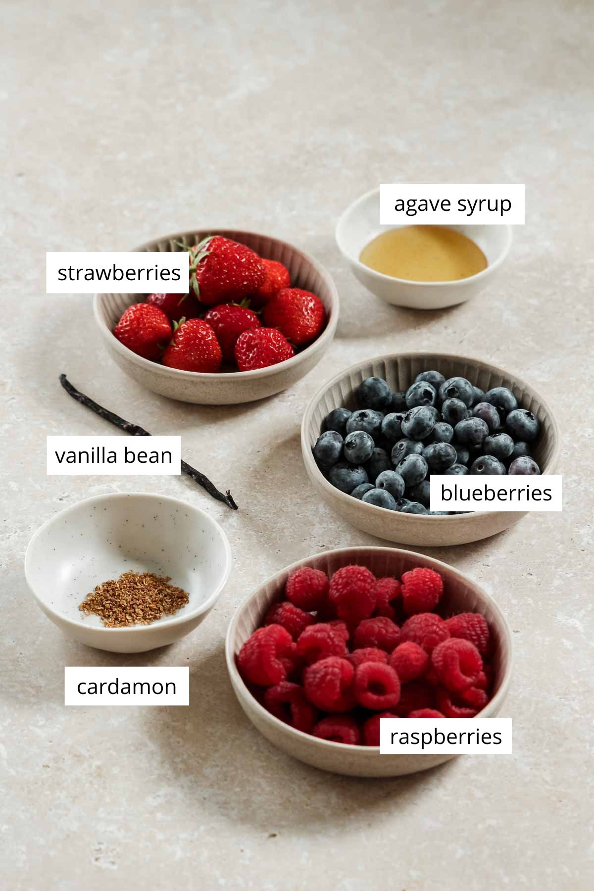 ingredients for healthy mixed berry compote on beige marble background.