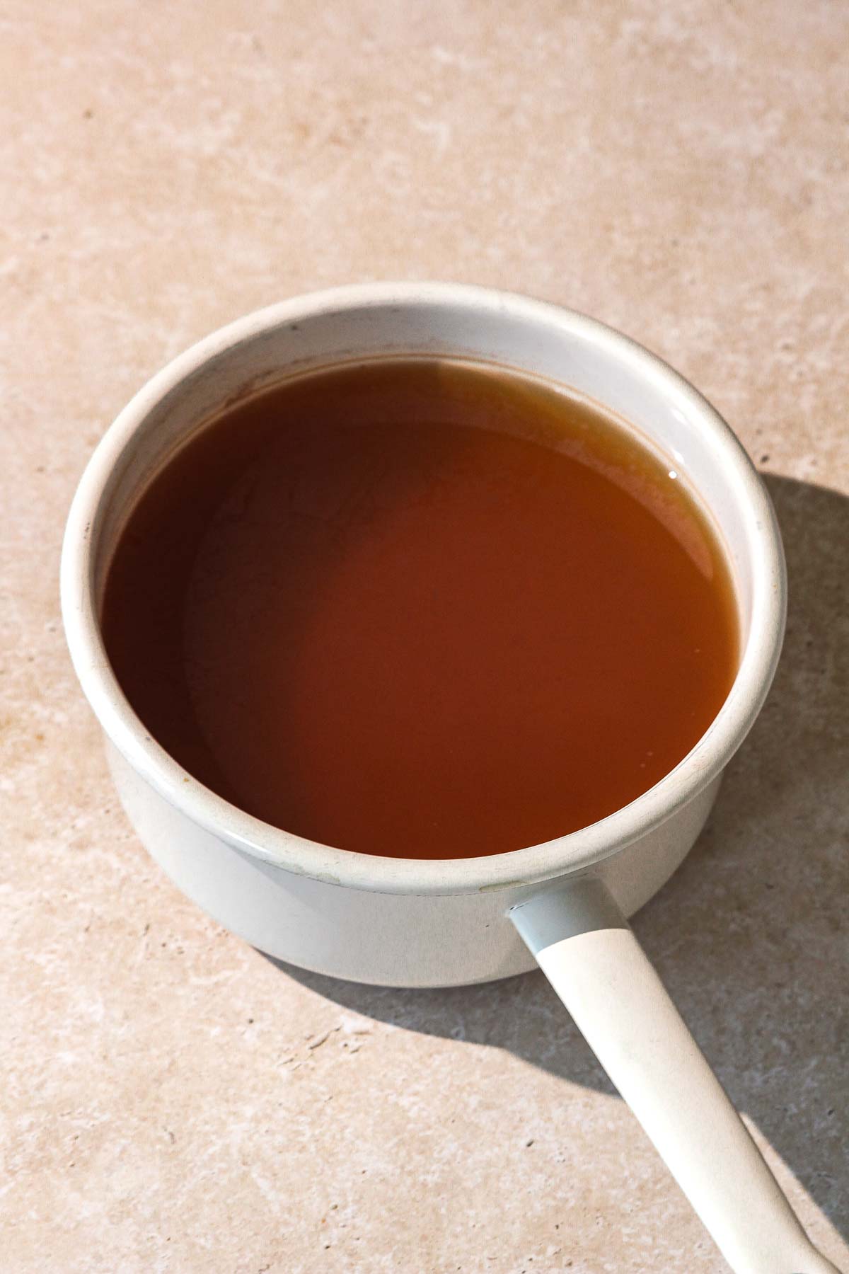 green tea in white saucepan on beige background.