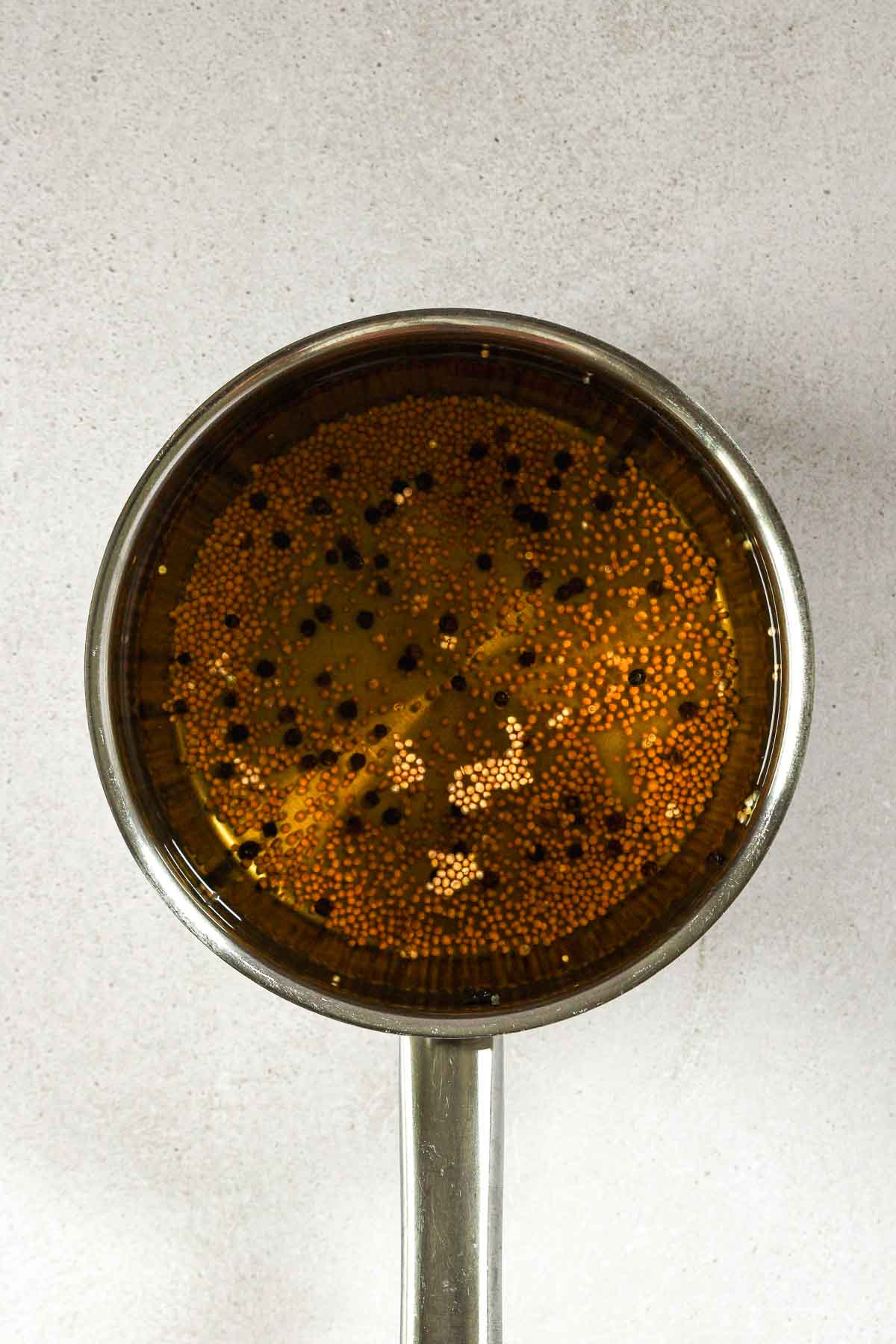 seasoned liquid for pickling cucumbers with white wine vinegar, pepper, mustard seeds and maple syrup.