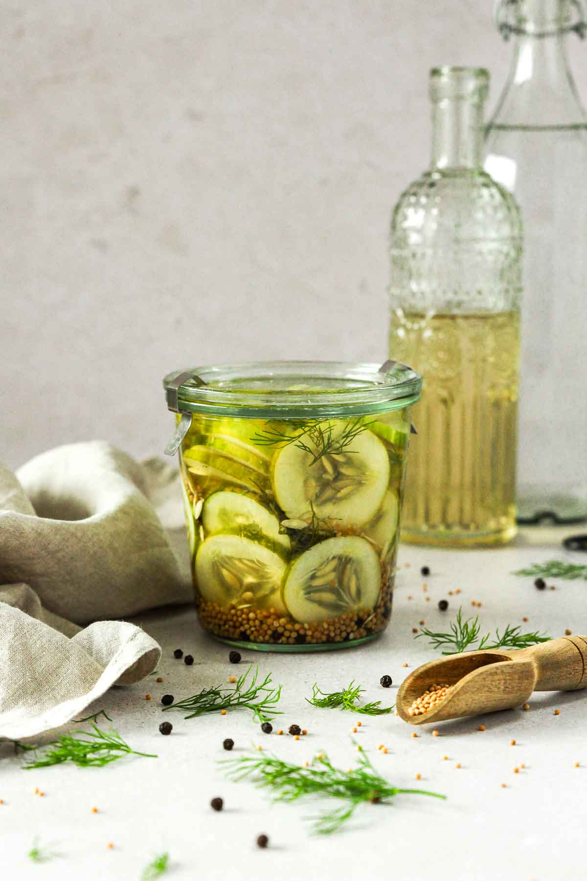 easy pickled cucumber slices on grey background with herbs spices, vinegar and linen.