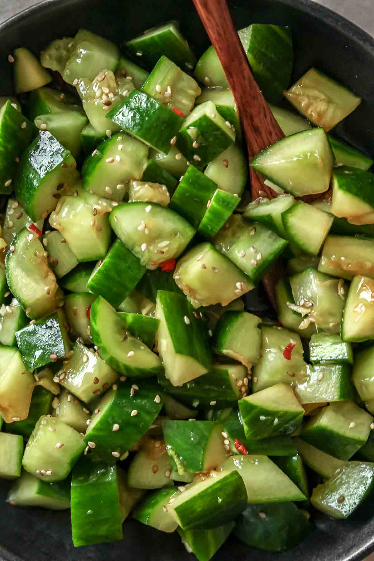 close up of spicy cucumber salad in black bowl.