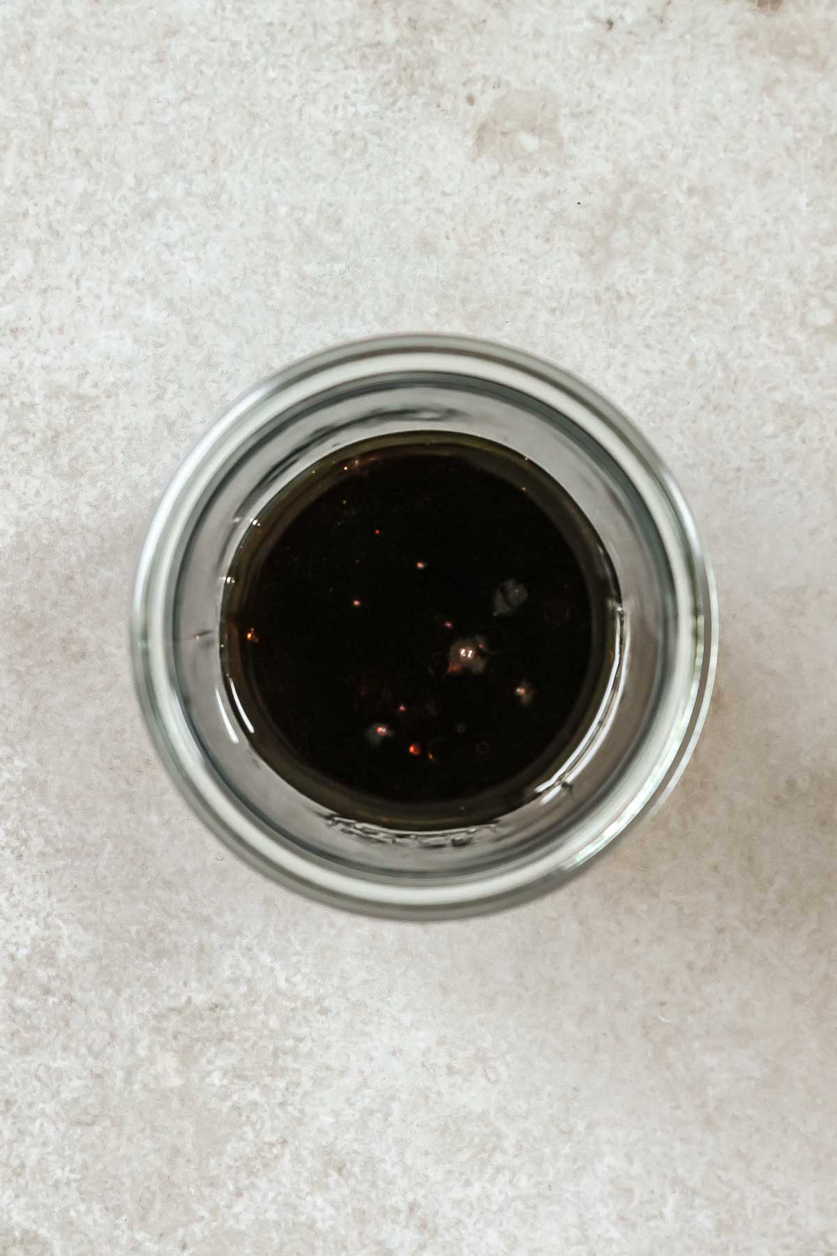 Asian dressing for cucumber salad in weck jar on beige background.