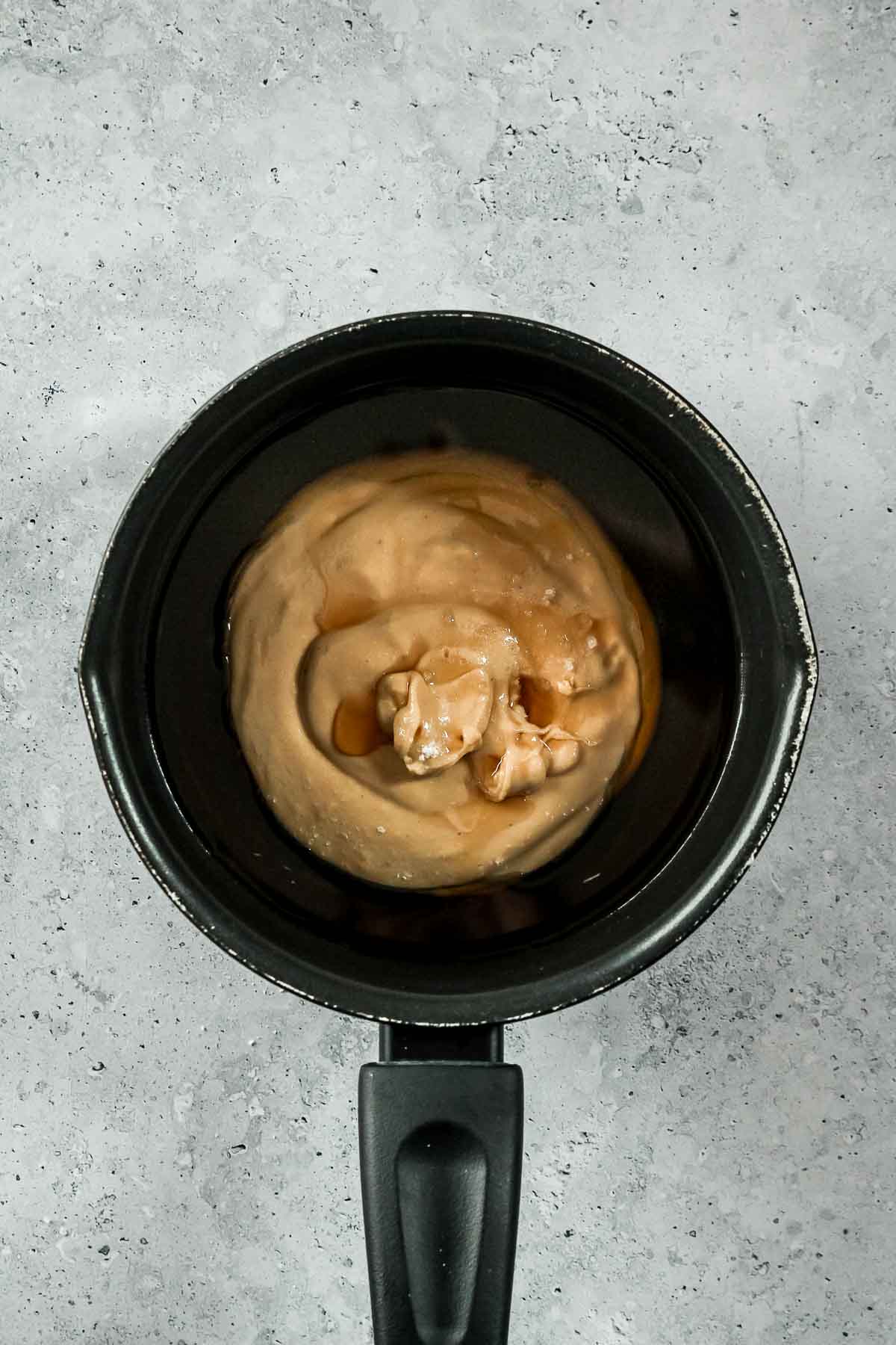 cashew butter, maple syrup and water in black saucepan for caramel.