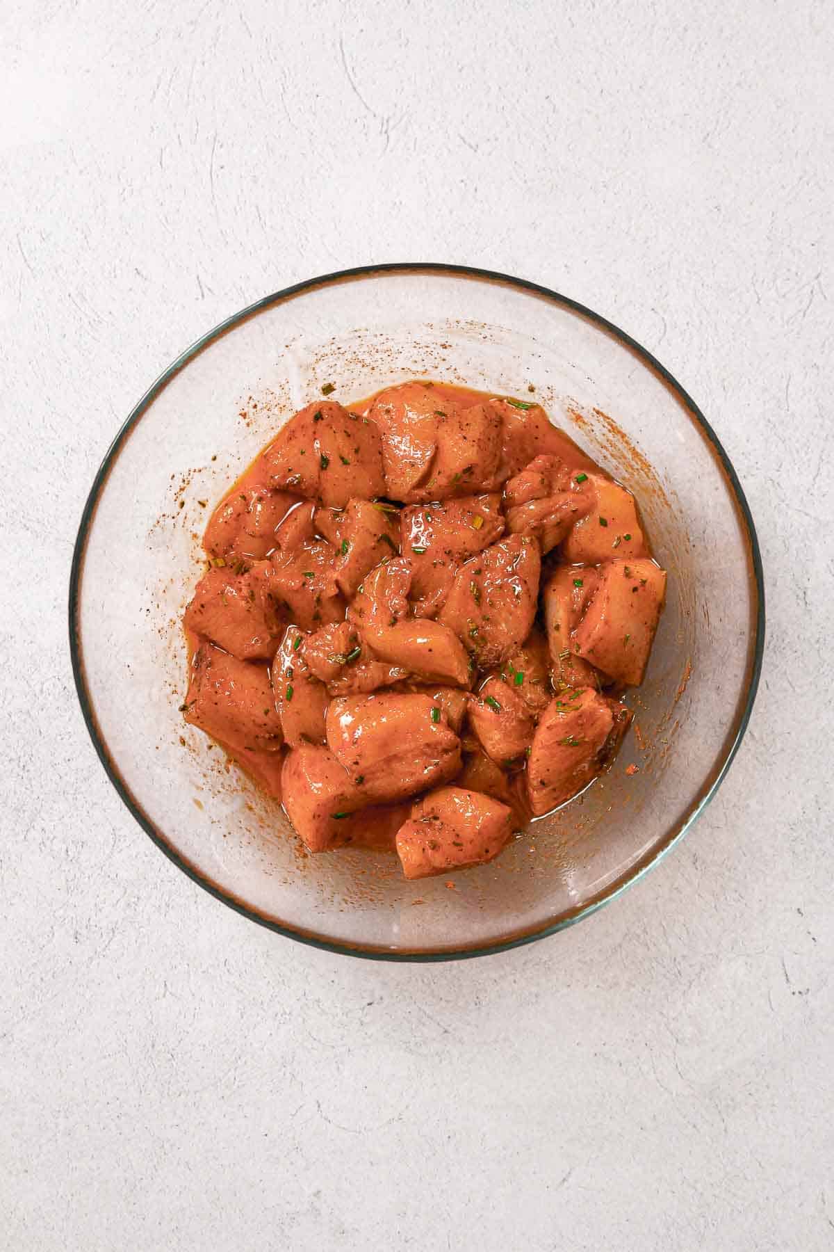 marinated chicken cubes in glass bowl.