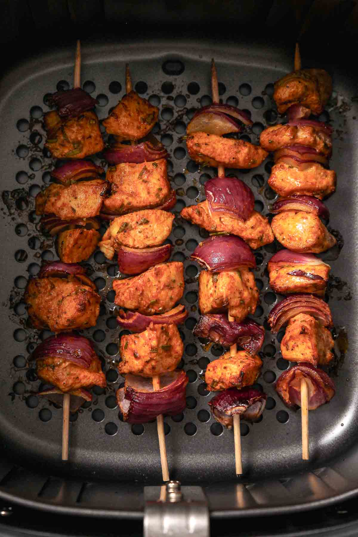 chicken skewers with red onion in air fryer ready to serve.