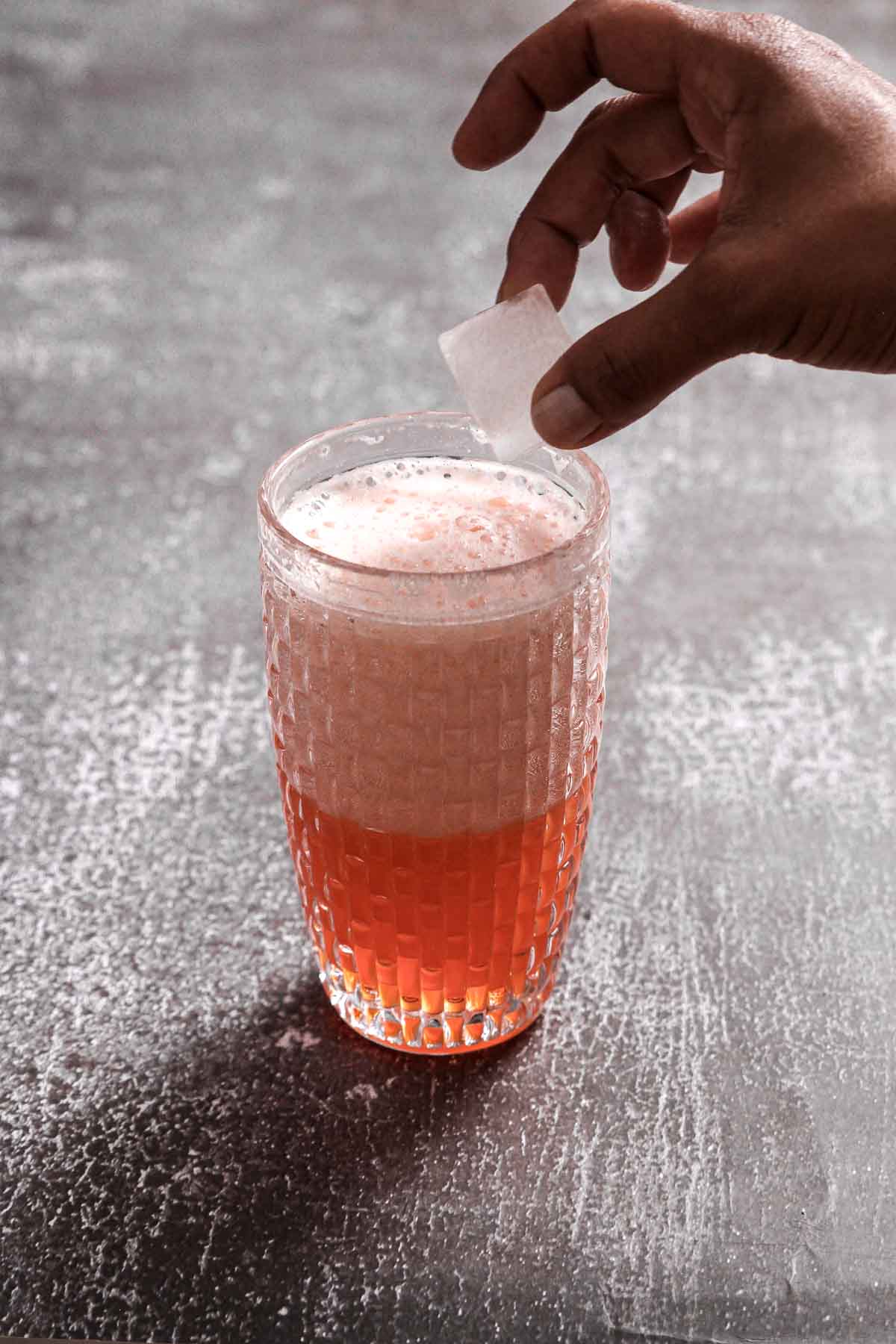 putting ice cubes into cocktail shaker with aperol sour after dry shake.